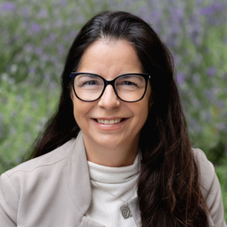 Headshot of Cassandra McGarvie, a smilley women with brown hair and black framed glasses