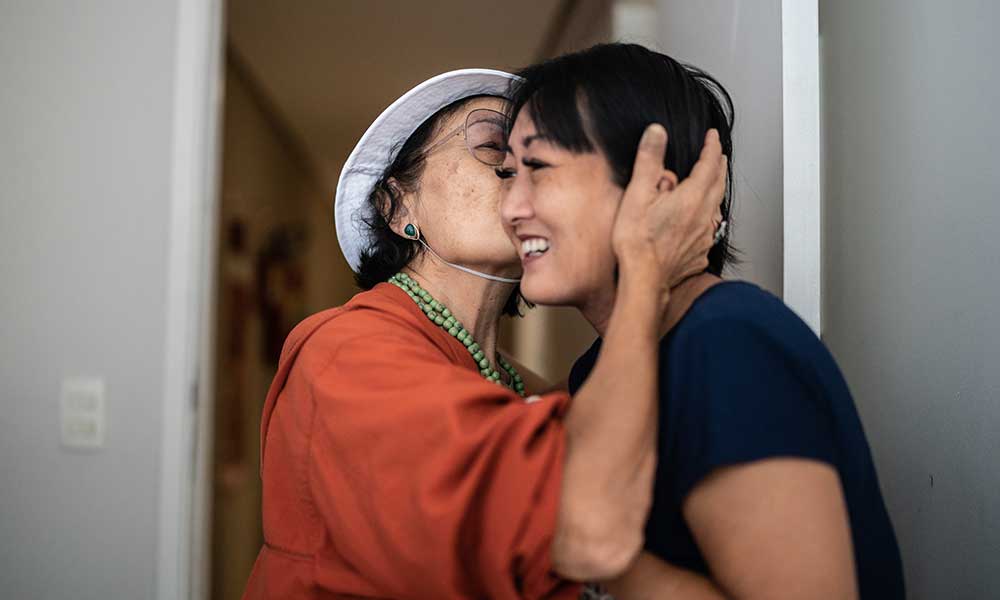 Mom kissing her daughter on the cheek upon coming home