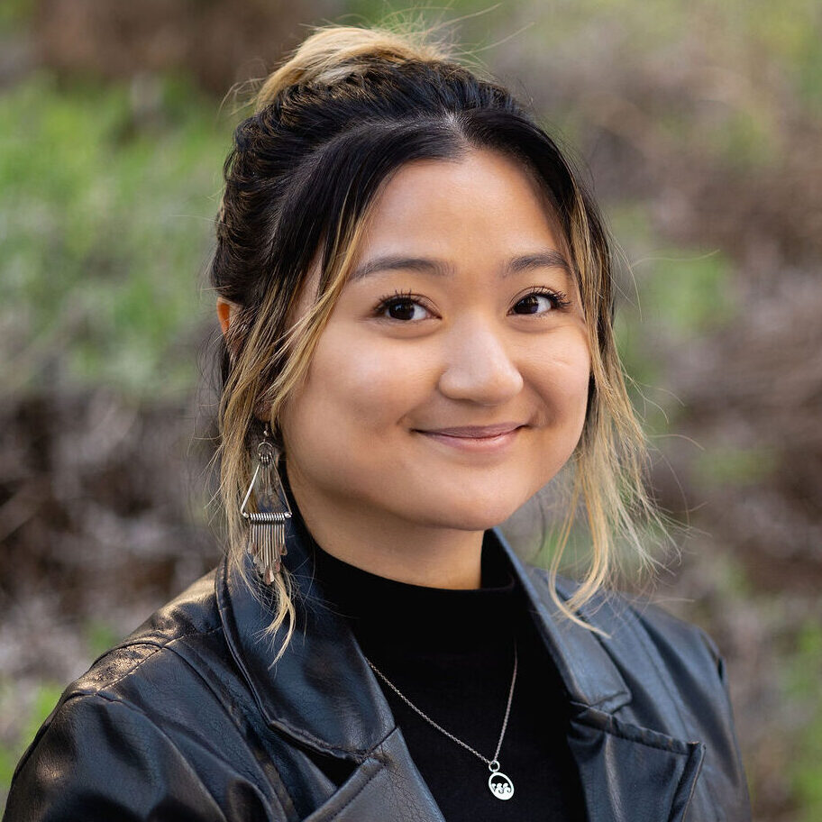 Headshot of Kim Regala. She has black and blonde hair tied up in a bun, and is wearing a black leather blazer on top of a black top.