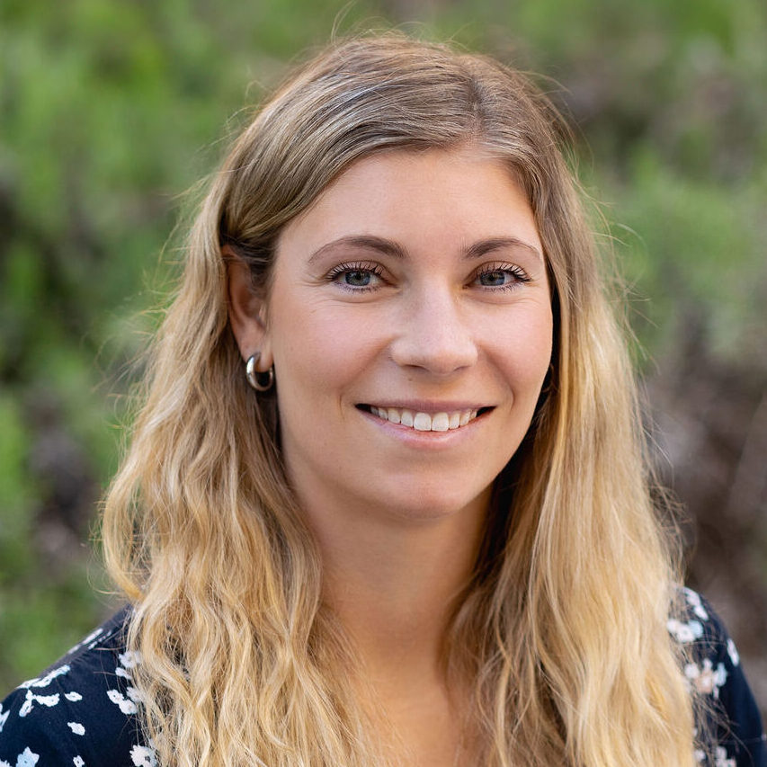 Headshot of Laura Hudson. She has long blonde hair and is wearing a dark printed top.