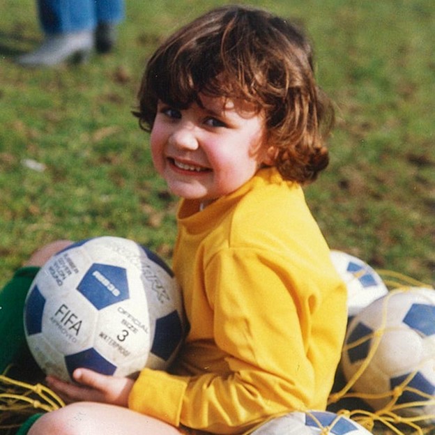 A child is pictured in a yellow shirt, holding a soccer ball, smiling.